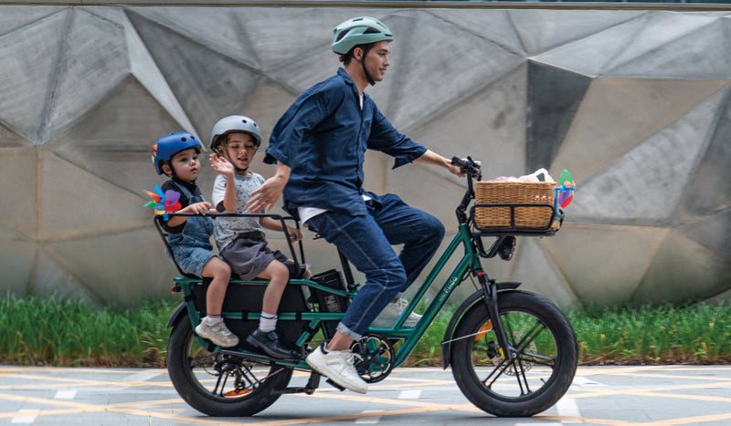 Ein Mann fährt mit zwei Kindern ein Fiido T2 Elektrofahrrad
