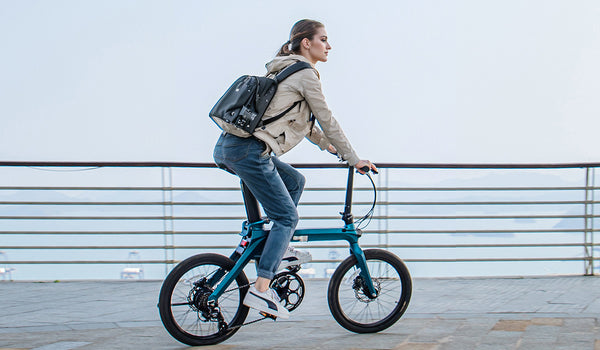 Frau fährt mit dem Elektrofahrrad Fiido X auf einem Holzsteg.