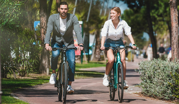 Ein Paar fährt auf Fiido C22 E-Bikes durch einen Park.