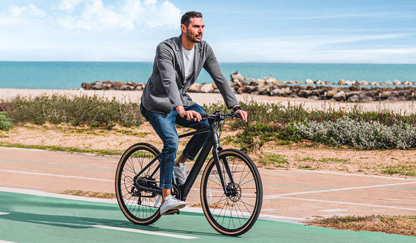 Ein Mann fährt mit einem Fiido C21-Elektrofahrrad am Meer entlang.