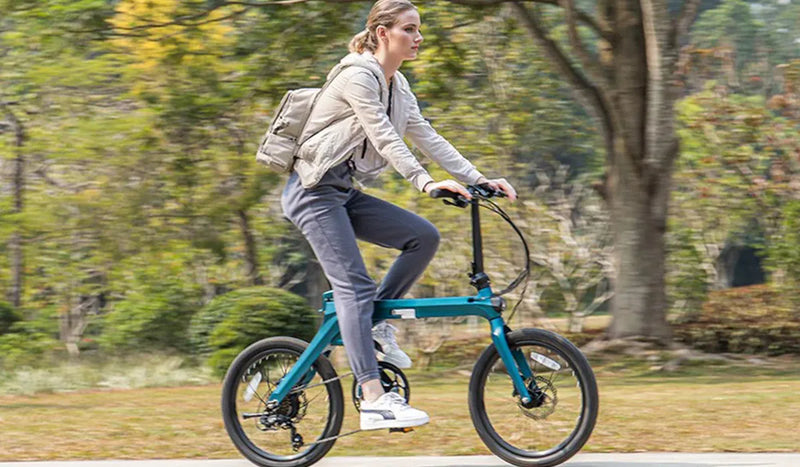 Eine Frau fährt mit einem Fiido X-Elektrofahrrad durch einen üppigen Park