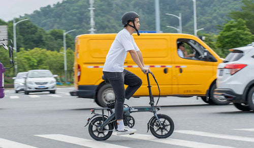 Ein Mann überquert die Straße mit einem Fiido L3-Elektrofahrrad