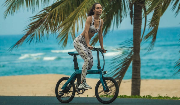 Eine fitte Frau fährt mit einem Fiido D11 Elektrofahrrad am Strand.