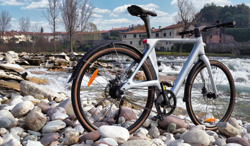 Fiido Air ultraleichtes E-Bike aus Carbonfaser, präsentiert an einem felsigen Flussufer neben fließendem Wasser.