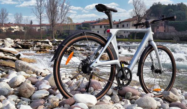 Fiido Air ultraleichtes E-Bike aus Carbonfaser, präsentiert an einem felsigen Flussufer neben fließendem Wasser.