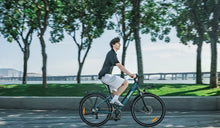 Ein Mann fährt mit einem leichten Fiido City-E-Bike auf einer Stadtstraße.